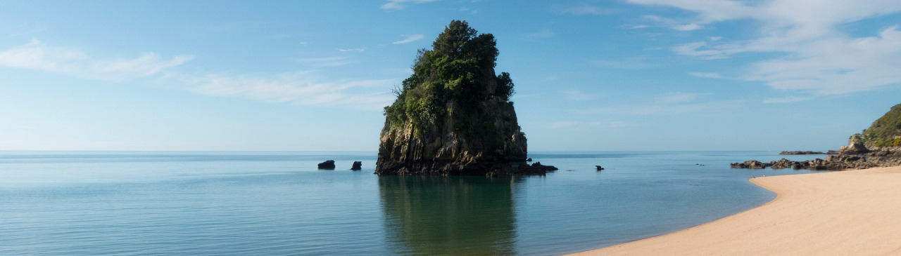 Blick auf den Strand mit einzelnem Felsblock im Wasser